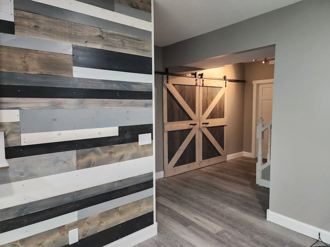 Finished reclaimed-wood accent wall and barn doors in the basement remodel