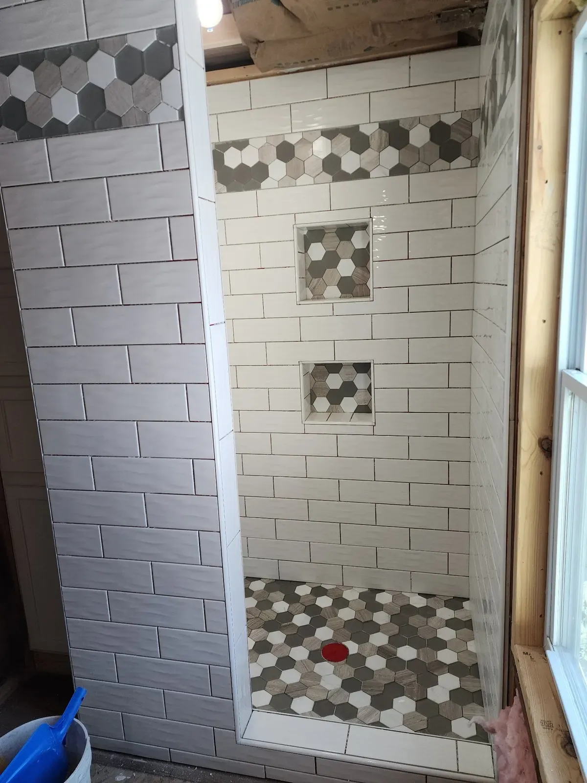 Subway tile walls and hex-accent niches during the cabin shower installation