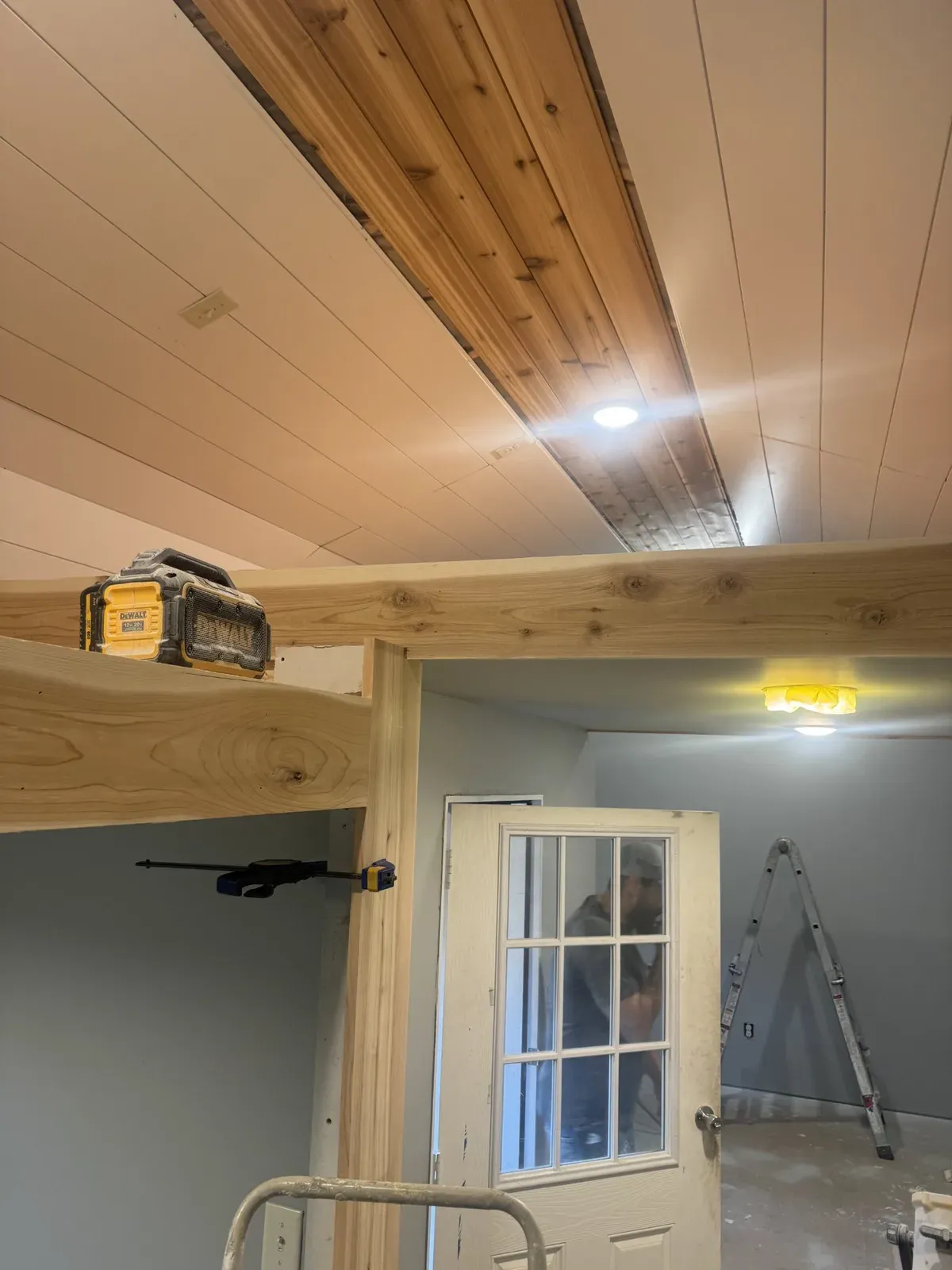 Finished cedar ceiling and exposed beams above a glass-pane door