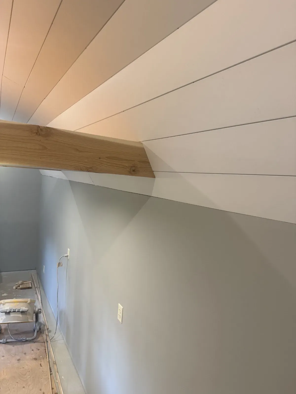 Detail of the white shiplap ceiling meeting the exposed wood beam