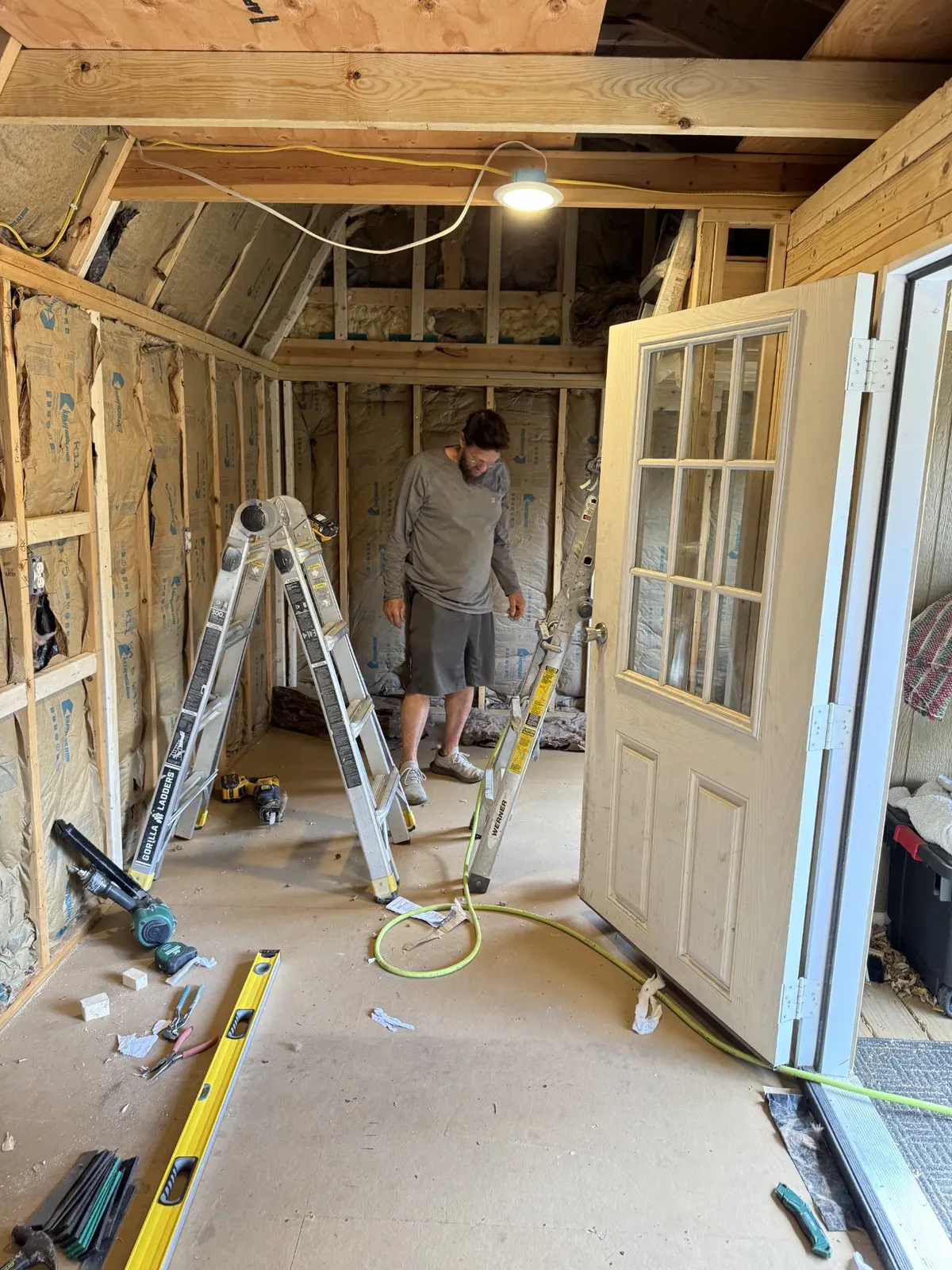 Insulated shed walls and ceiling framing with the entry door set in place