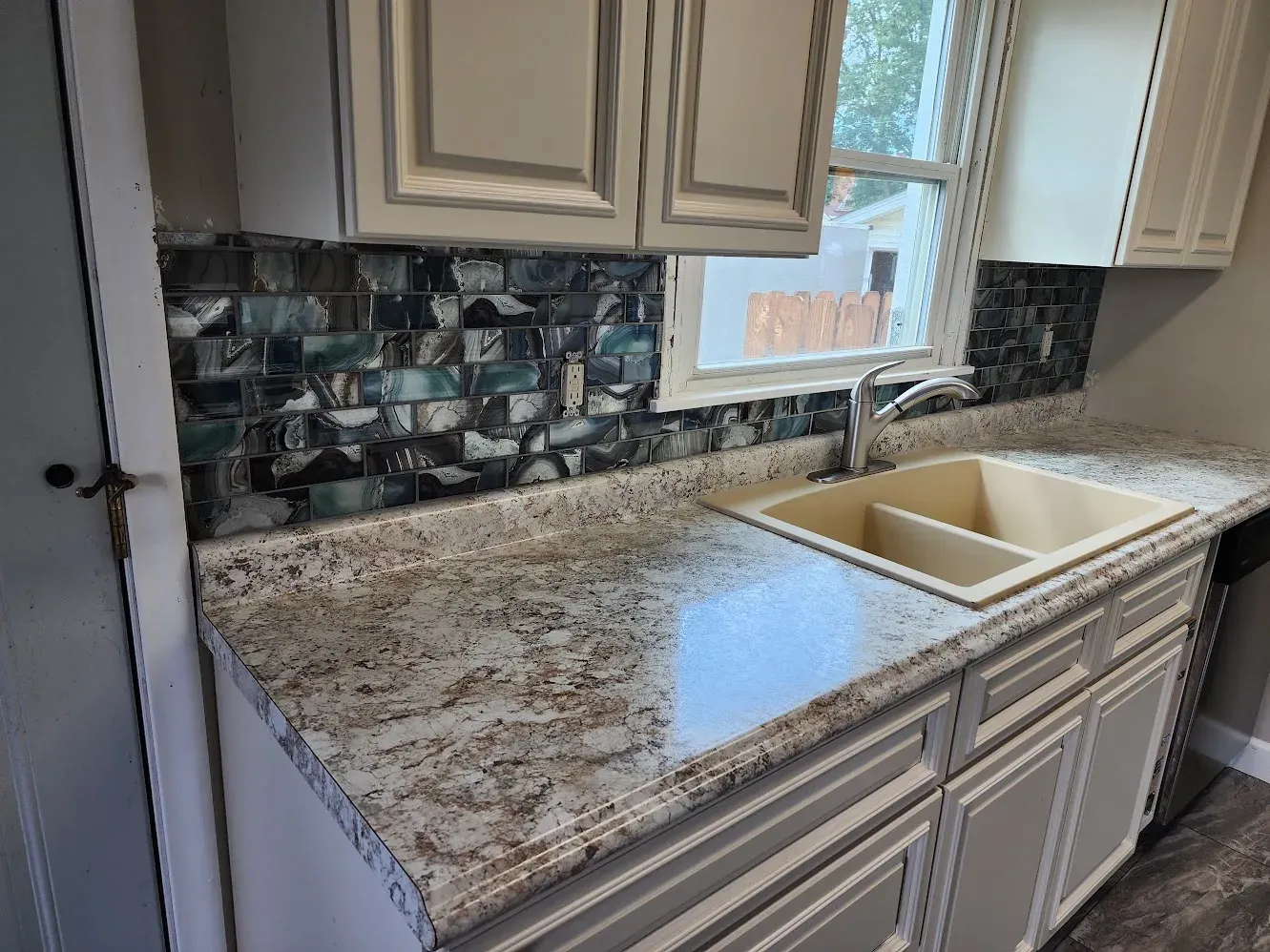 Close view of the finished sink, counter, and mosaic tile backsplash