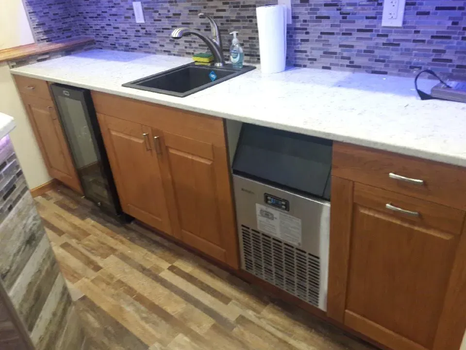 Finished basement wet bar lower cabinets, sink, and appliances