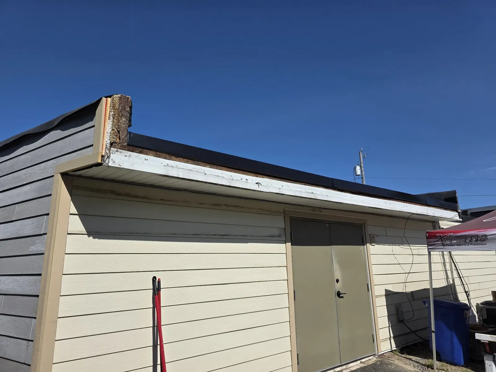 Rear of the performance center before the re-siding, with a rotted board end exposed at the roofline rake