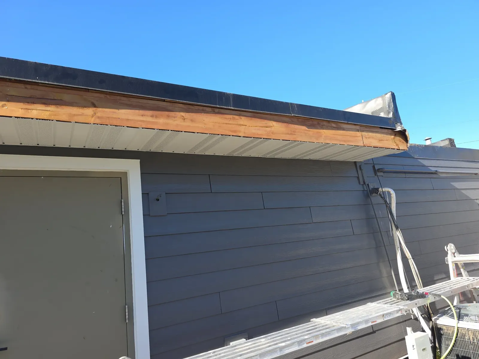 New vented soffit installed above the dark siding, with the fascia board still to be finished