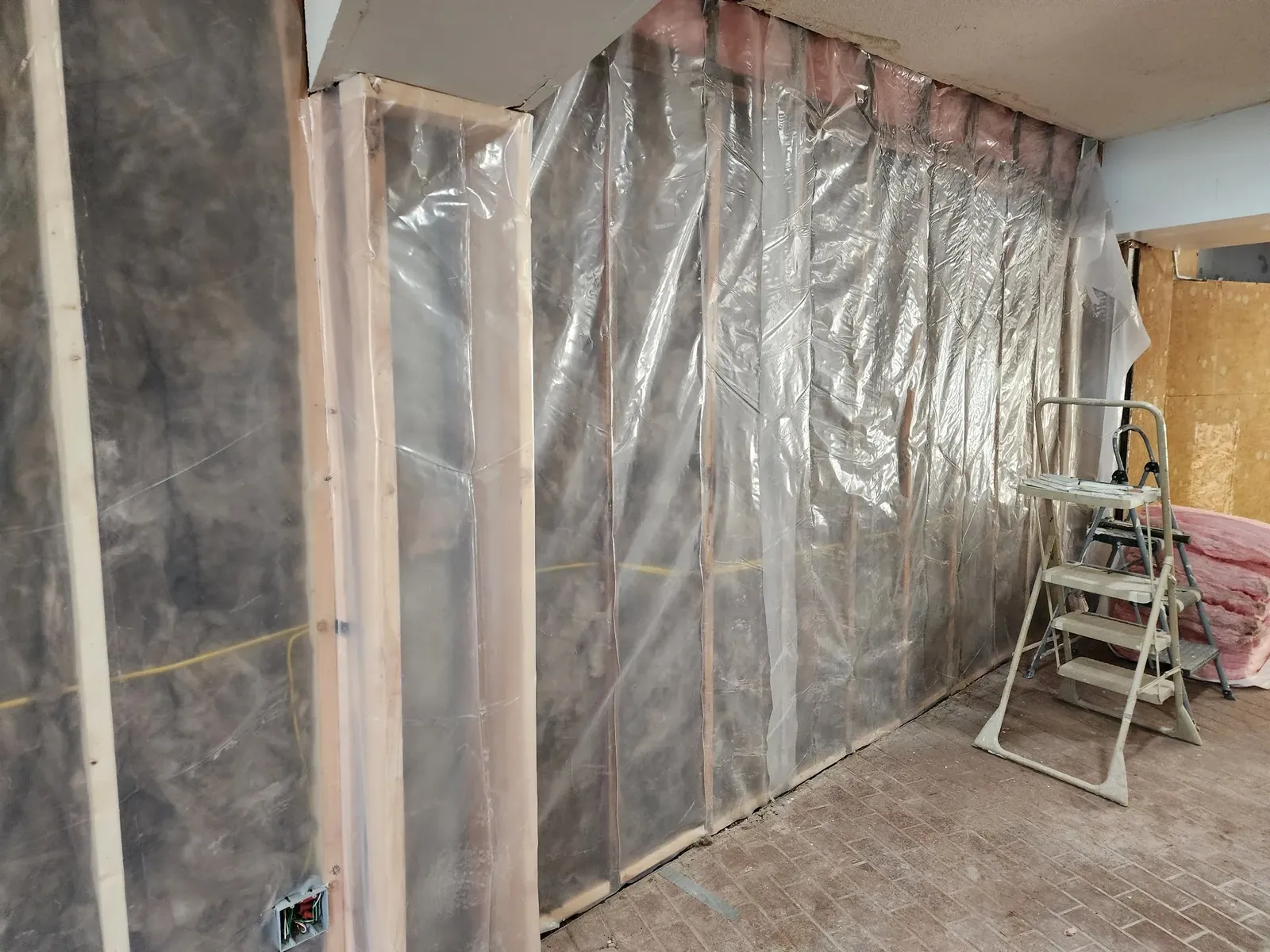 Wall covered with a new clear vapor barrier during the commercial gym remodel