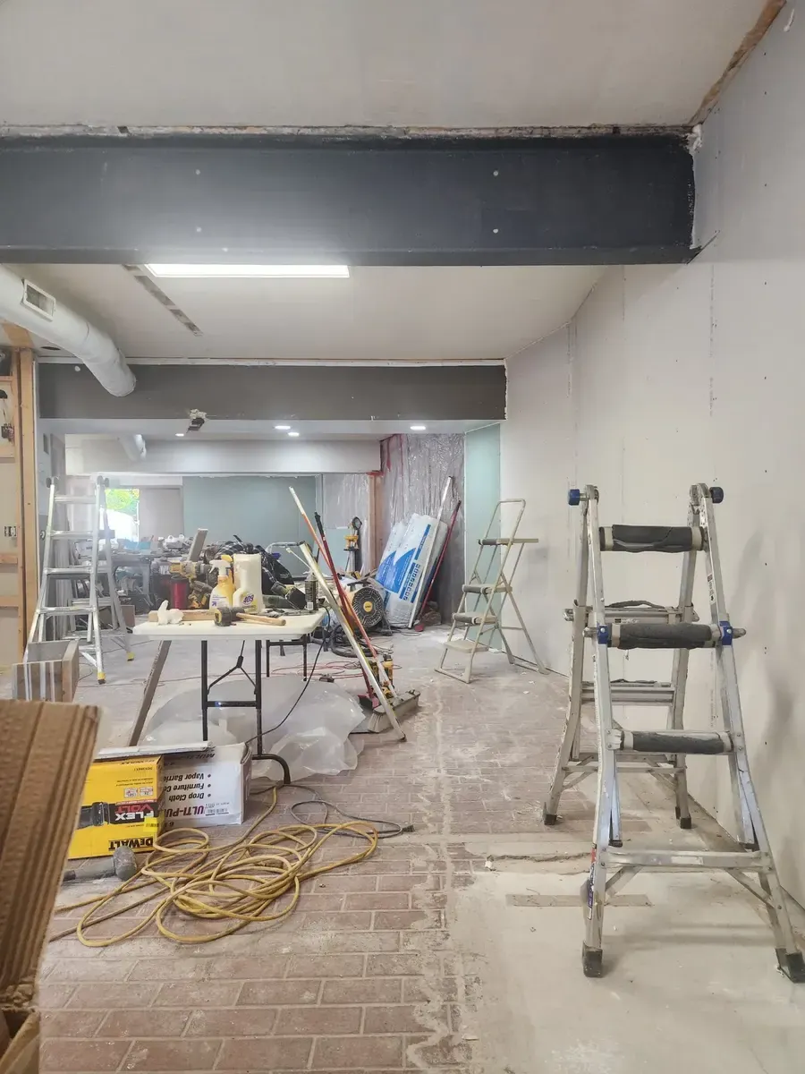 Open gym interior with saws, ladders, and materials during the build-out