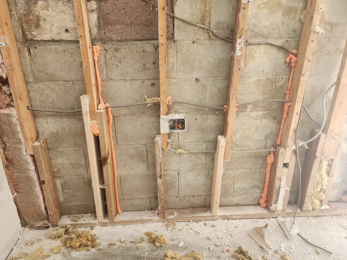 Utilities exposed in wall framing beside the block wall