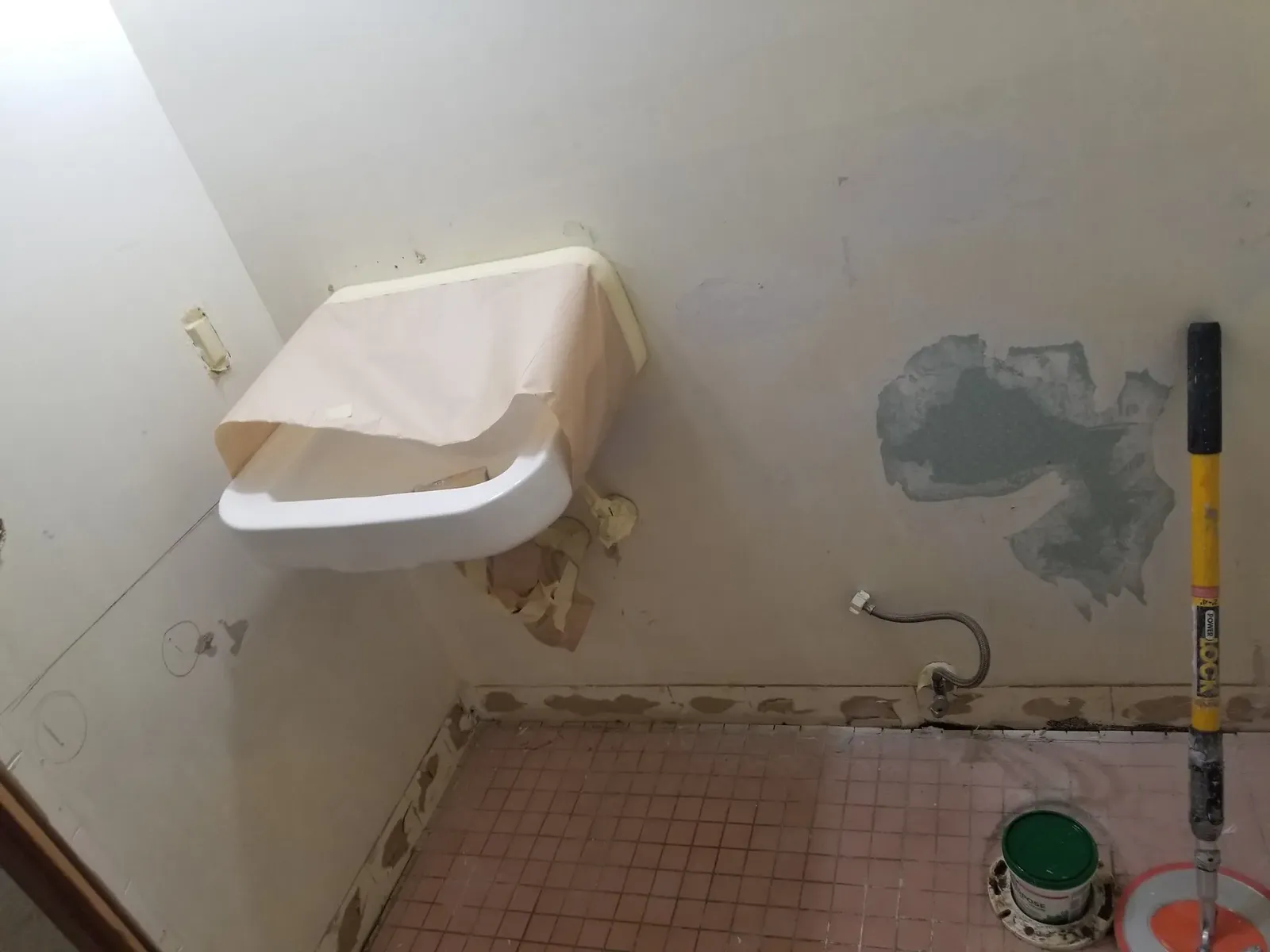 Original church powder room with a wall-mounted sink and pink mosaic floor tile before the refresh